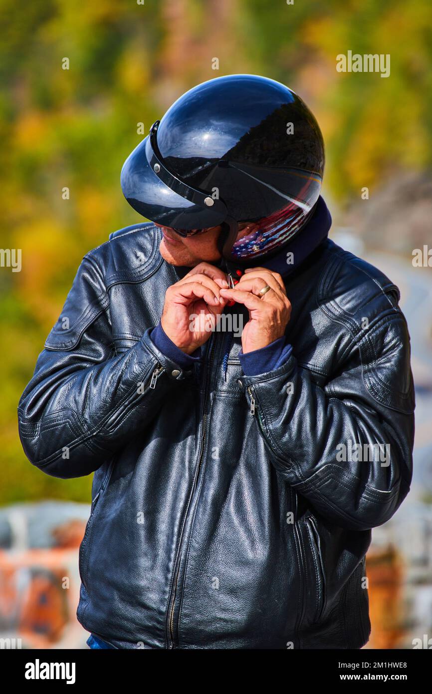 Ritratto verticale di motociclista sconosciuto indossando casco nero con bandiera americana e giacca in pelle nera Foto Stock