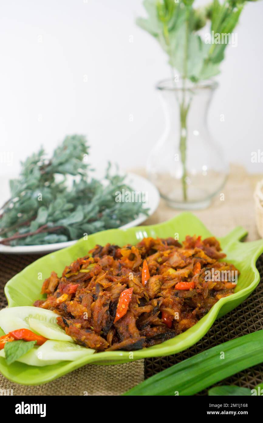 Pampis Tongkol/Cakalang, piatto di pesce tradizionale del Manado con pesce speziato, servito su un piatto verde Foto Stock