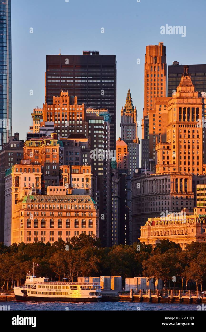 Empire state Building attraverso le strade di New York City dal largo della costa con luce dorata al tramonto Foto Stock