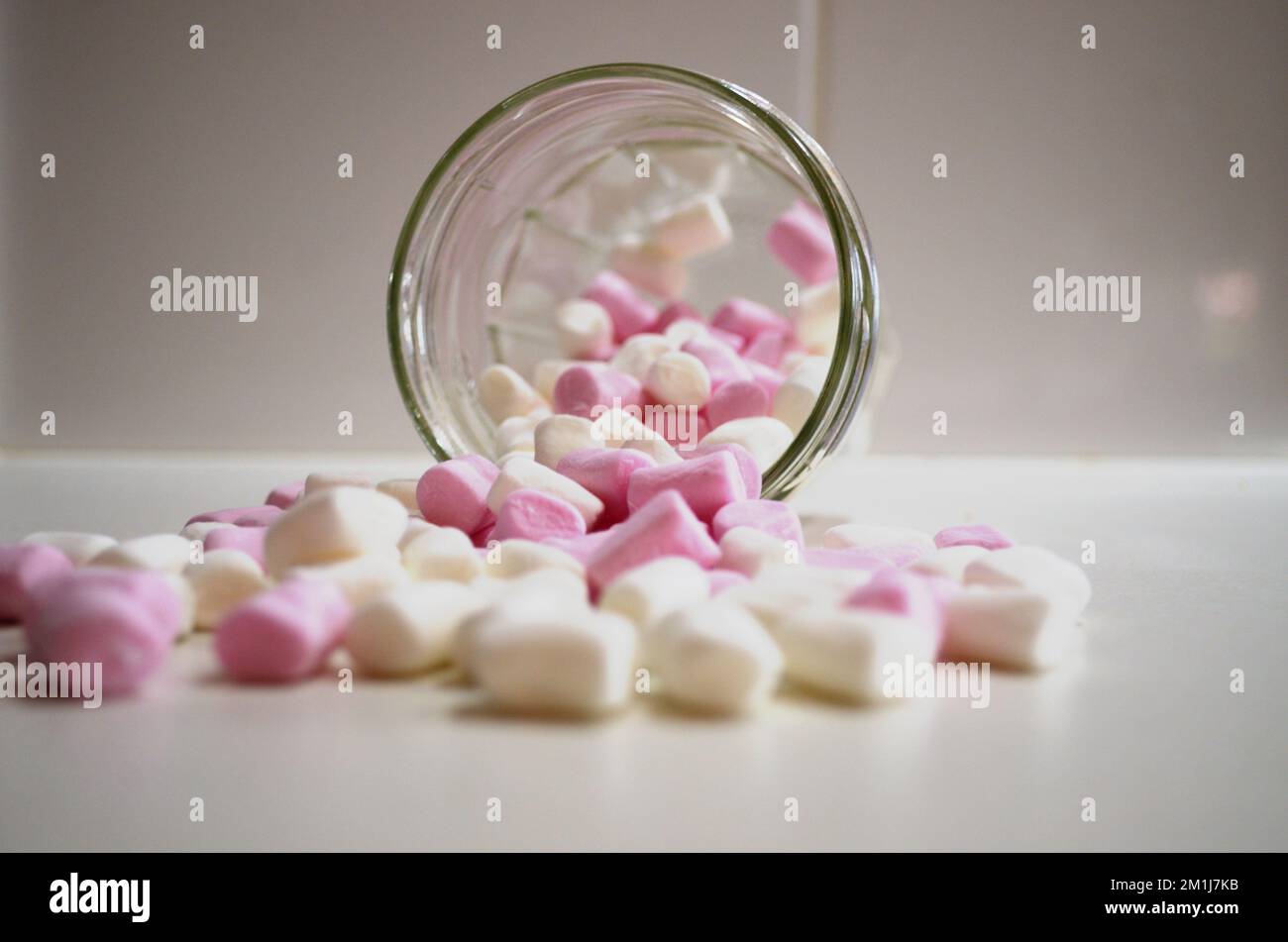 Mini, piccoli Marshmallows versati dal vaso sul banco della cucina Foto Stock
