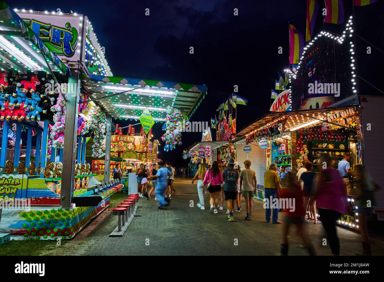 Venditori di giochi e cibo linea strada a piedi di notte a carnevale County fiera Foto Stock