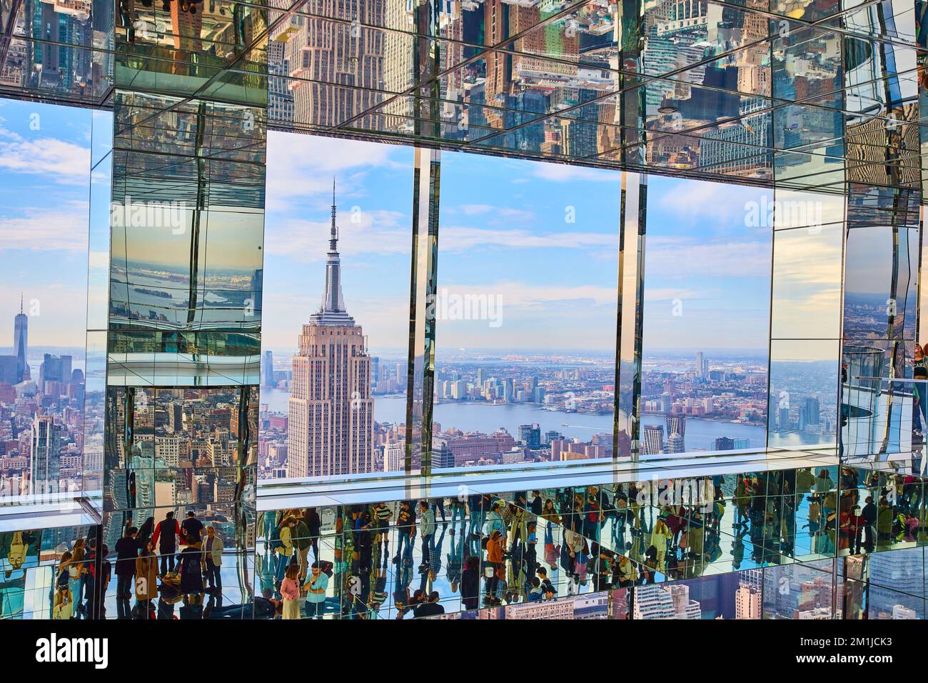 Lo splendido Empire state Building è visto in alto in un grattacielo riflettente con i turisti Foto Stock
