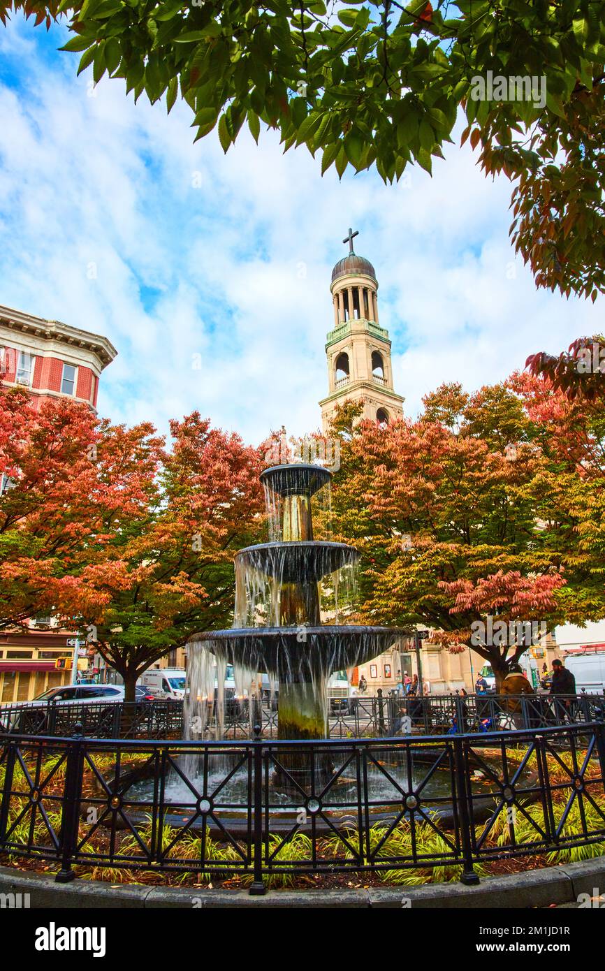 New York City splendida fontana circondata da alberi autunnali con chiesa cristiana campanile dietro Foto Stock