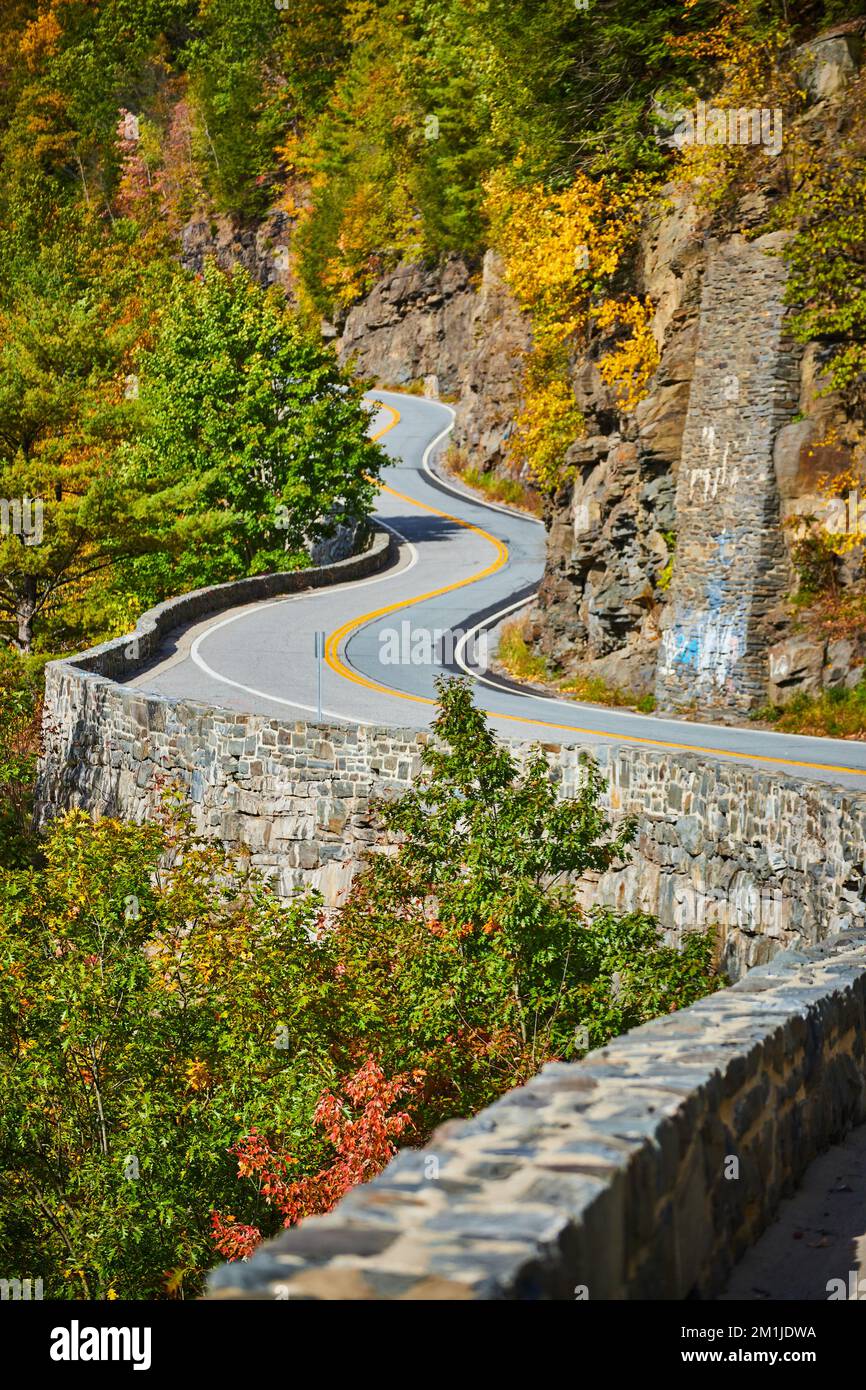 Bella strada tortuosa con muro di pietra lungo il bordo della scogliera in montagna Foto Stock