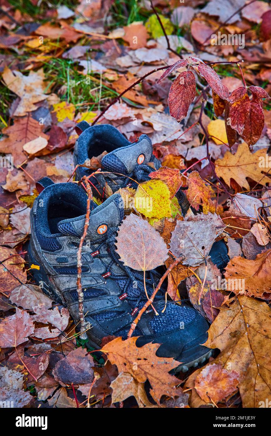 Coppia di scarpe nere abbandonate coperte da foglie autunnali per sentiero Foto Stock