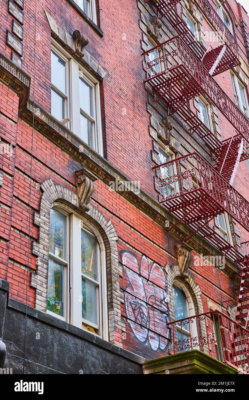 Si affaccia su un vecchio edificio in mattoni a New York City con gradini in metallo sul lato Foto Stock