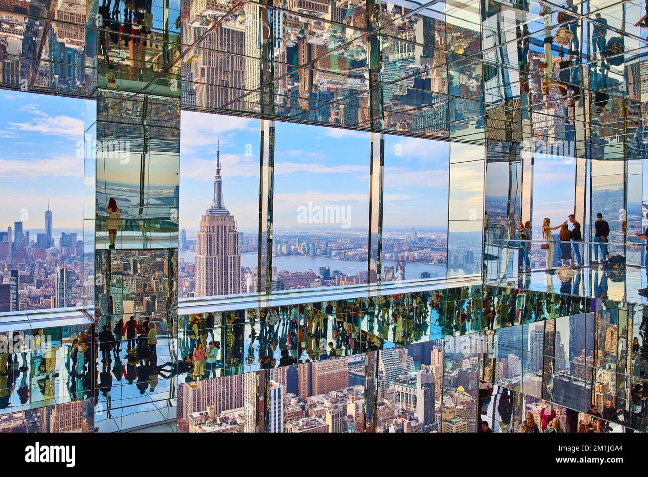 I turisti godono di vista dell'Empire state Building in alto sulla cima di un grattacielo specchio delle sale di riflessione a New York City Foto Stock