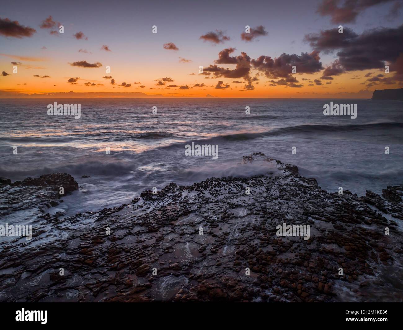 Dawn Seascape con nuvole, piattaforma rocciosa, onde di buone dimensioni e molta atmosfera a North Avoca Beach sulla costa centrale, NSW, Australia. Foto Stock