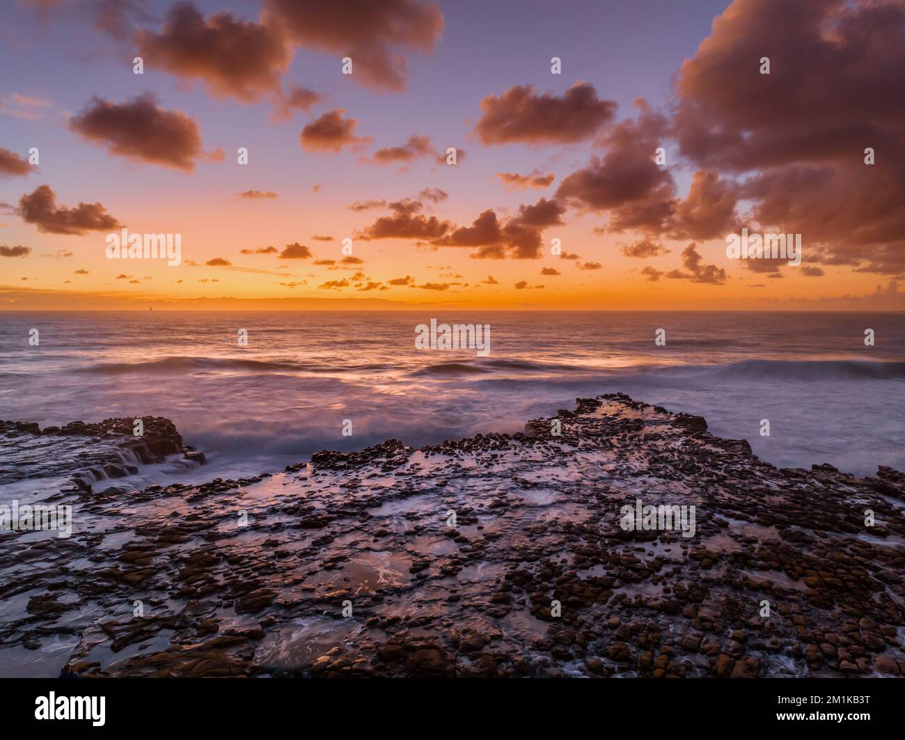 Dawn Seascape con nuvole, piattaforma rocciosa, onde di buone dimensioni e molta atmosfera a North Avoca Beach sulla costa centrale, NSW, Australia. Foto Stock