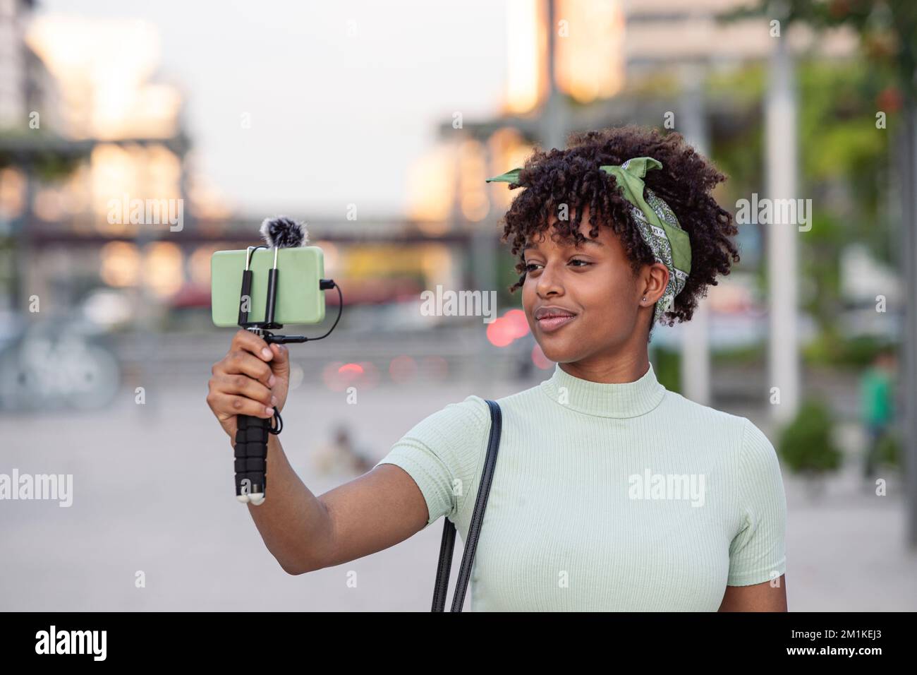 Ritratto di giovane afroamericana in streaming dal vivo mentre si cammina per la città. concetto di blogger giovane, spazio di copia. Foto Stock