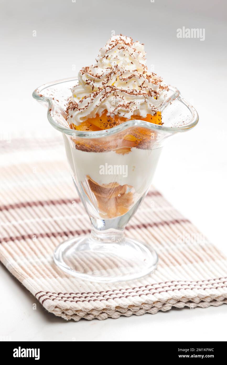 gelato con pesca stufata e panna montata Foto Stock