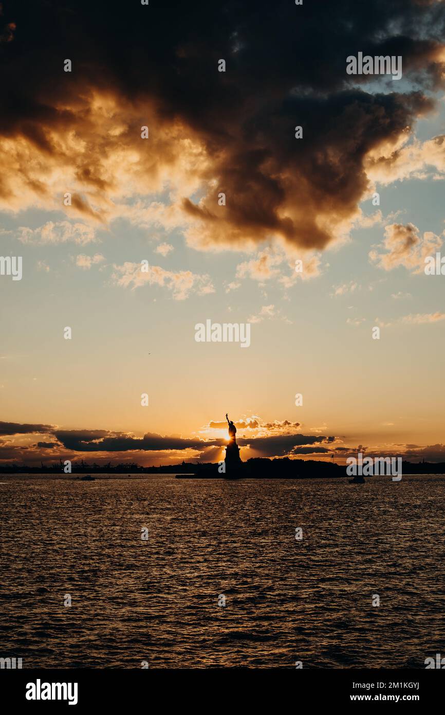 Statua della libertà al tramonto, con un caldo bagliore sulla sua superficie di rame e un cielo colorato a New York Foto Stock