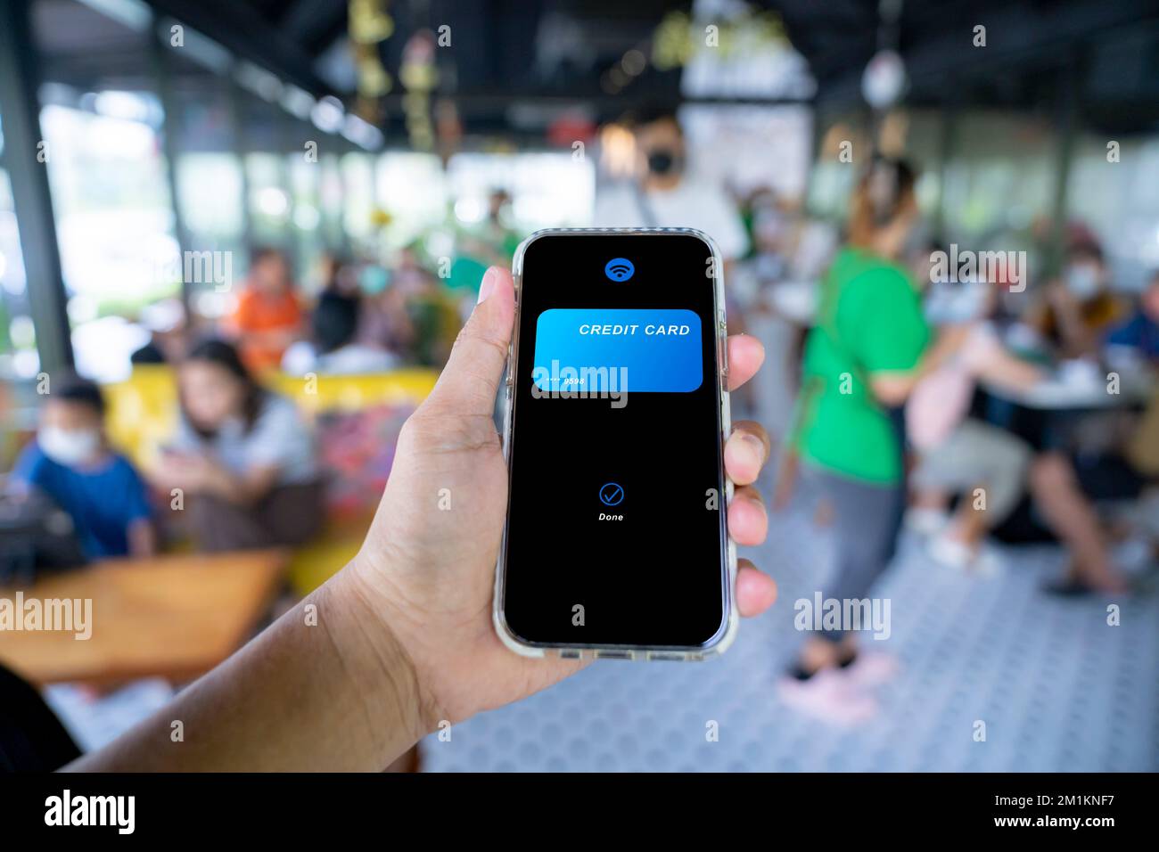 Mano che tiene il telefono cellulare con l'applicazione della carta di credito che effettua la transazione di pagamento. Foto Stock