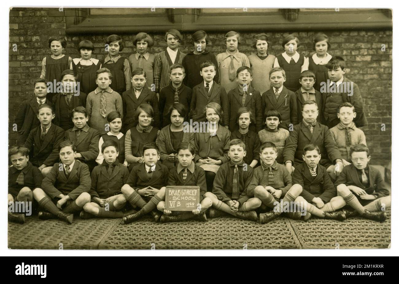 Cartolina originale degli anni '20 della Brae Street School V1B datata 1928 (su segno) ritratto di classe di gruppo all'esterno nel parco giochi della scuola, indossando uniformi miste e altre mode. Al contrario è scritto di età 12 anni. Liverpool, Merseyside, Inghilterra, Regno Unito Foto Stock