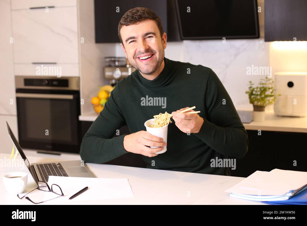 L'uomo mangia spaghetti istantanei mentre lavora a casa Foto Stock