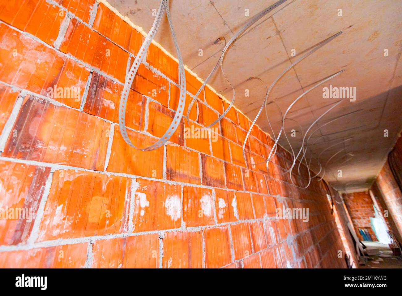 Pila di nastri di fissaggio zincati forati installati per il fissaggio di tubi, cavi, lampade o accessori elettrici, appesi al soffitto della costruzione Foto Stock