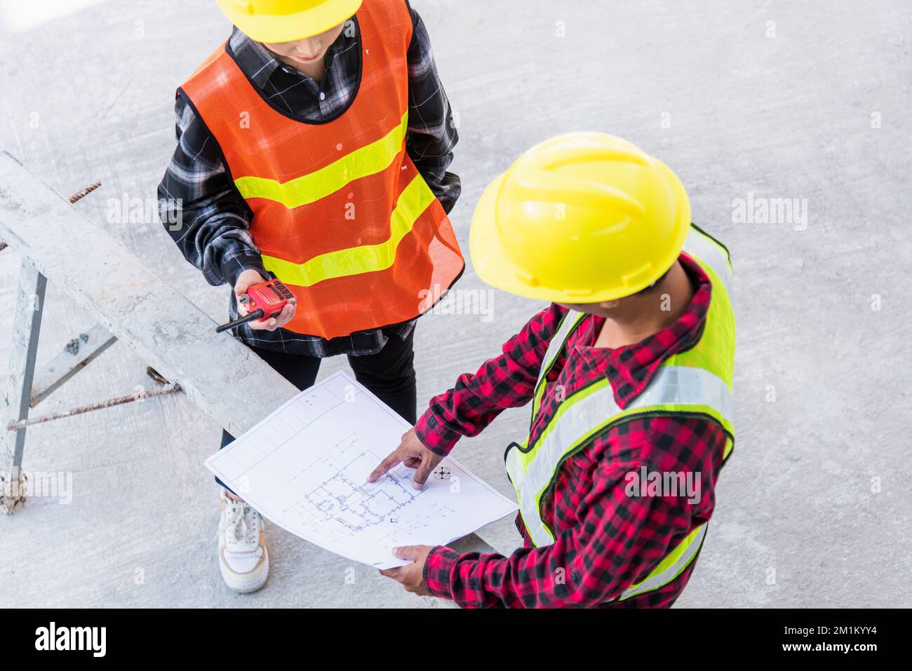 L'architetto e il cliente che discutono aiutano a creare un piano con il piano dell'edificio nel cantiere Foto Stock