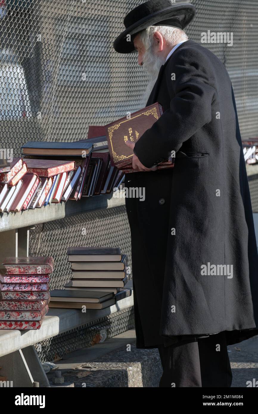 Un vecchio uomo ebraico hassidico fa shopping di libri in una vendita all'aperto a Brooklyn, New York City. Foto Stock