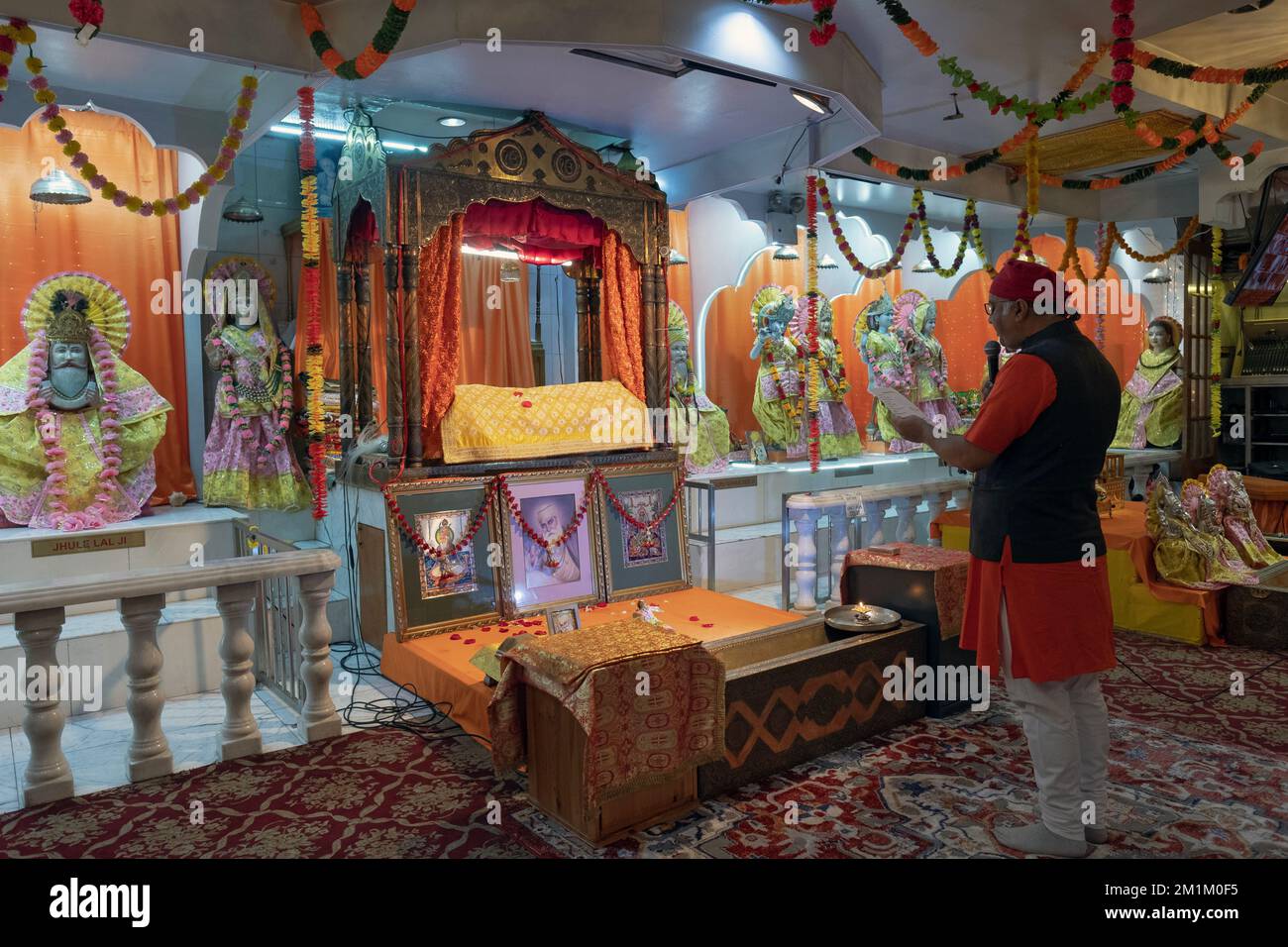 Un sacerdote indù legge messaggi personali in un servizio nel Satya Narayan Mandir a Woodside, Queens, New York. Foto Stock