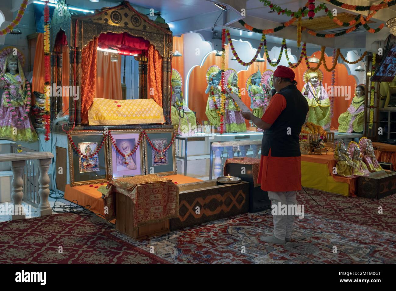 Un sacerdote indù legge messaggi personali in un servizio nel Satya Narayan Mandir a Woodside, Queens, New York. Foto Stock