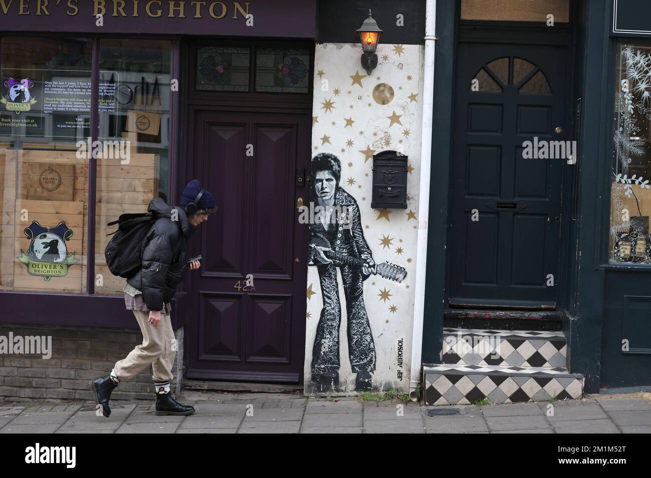 Un uomo passa davanti a un murale di David Bowie dipinto dall'artista JEF AEROSOL nella zona del Nord Laine di Brighton. Foto Stock