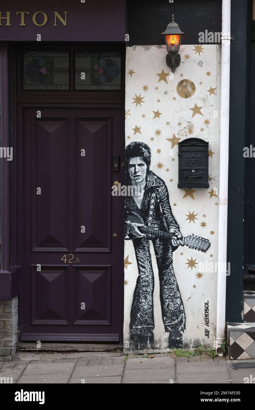 Un uomo passa davanti a un murale di David Bowie dipinto dall'artista JEF AEROSOL nella zona del Nord Laine di Brighton. Foto Stock