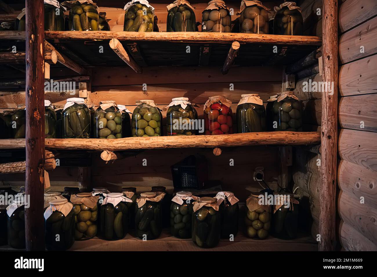 Conservazione delle verdure in una cantina calda per il periodo invernale. Vasetti di vetro con cetrioli sottaceto sulla mensola. Foto Stock
