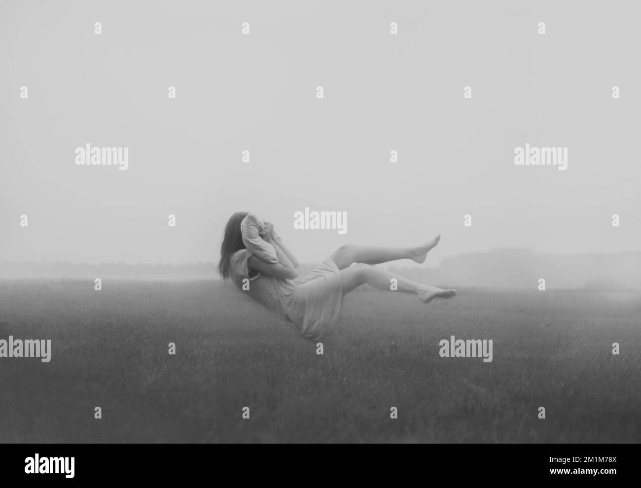 Giovane donna in un abito da notte levitating nell'aria e stipando un cuscino Foto Stock