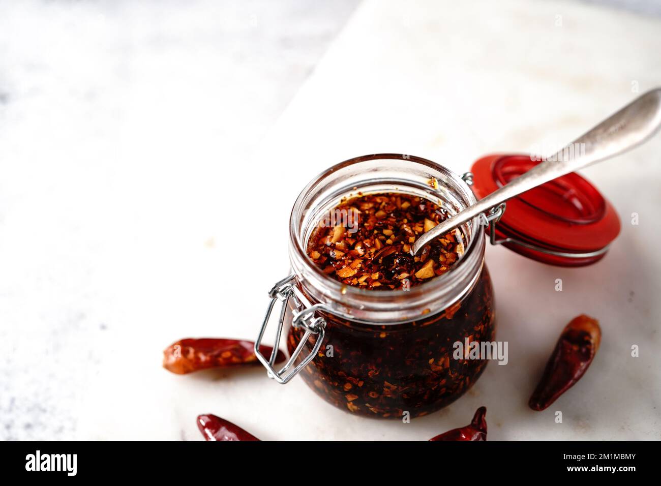 Olio di peperoncino asiatico fatto in casa in un vasetto di vetro, fuoco selettivo Foto Stock