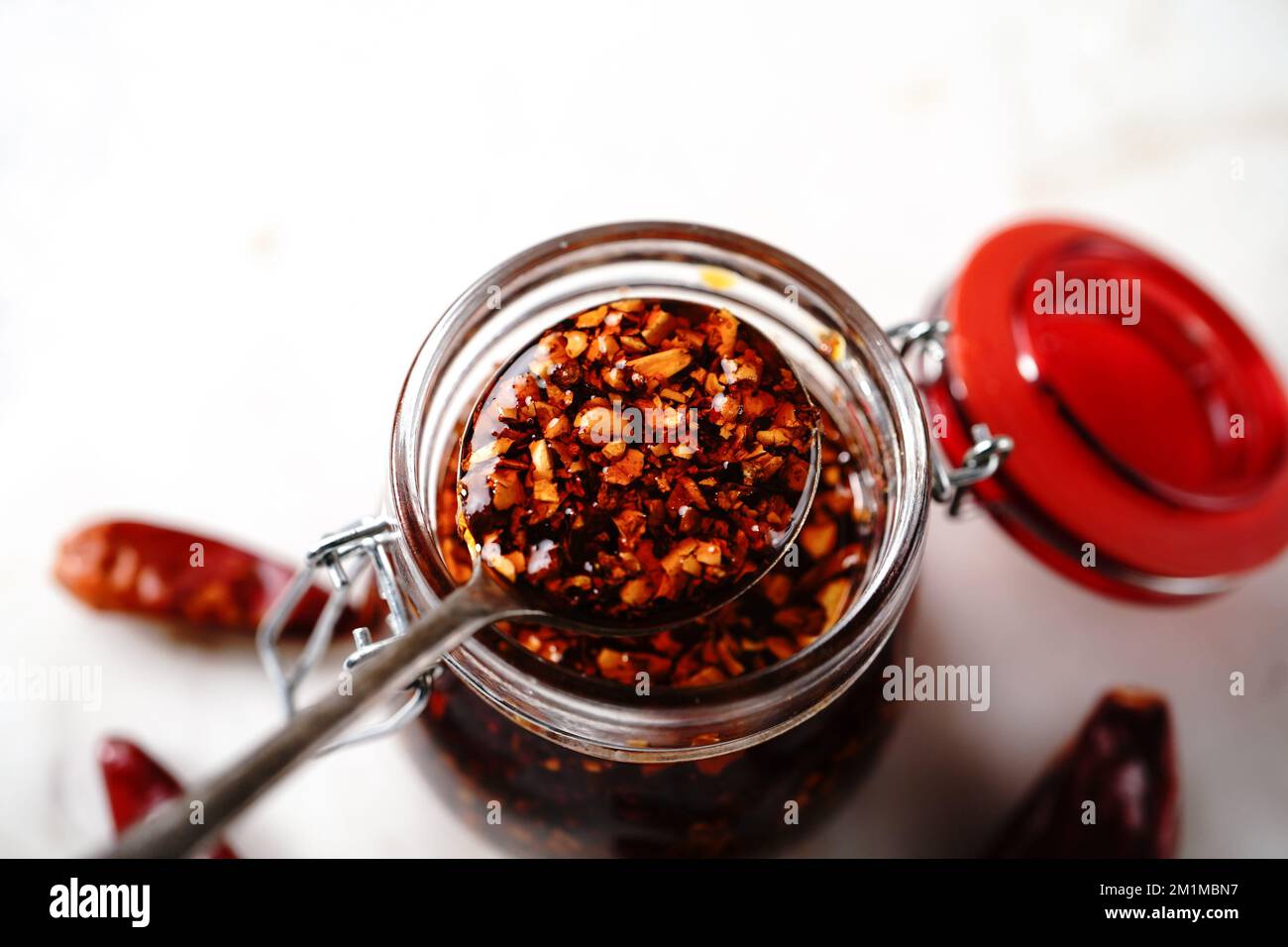 Olio di peperoncino asiatico fatto in casa in un vasetto di vetro, fuoco selettivo Foto Stock