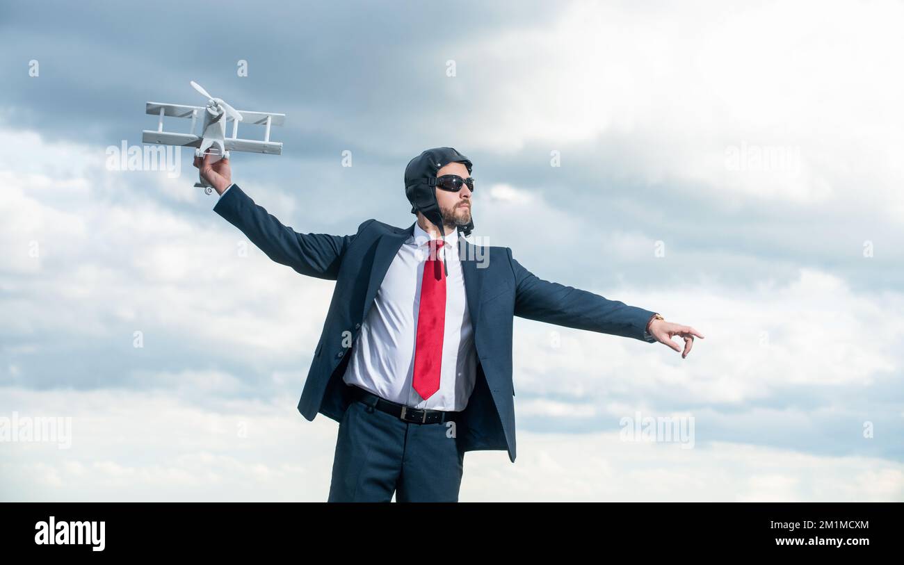 uomo d'affari in tuta e aereo cappello lancio giocattolo su sfondo cielo Foto Stock
