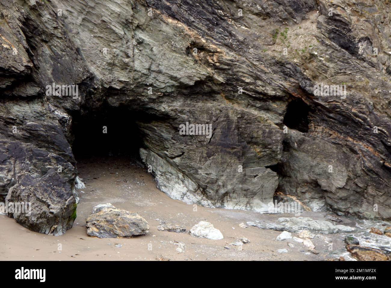 Merlin's Cave sotto il castello sull'isola di Tintagel da Tintagel Haven sul sentiero costiero sud-occidentale in Cornovaglia, Inghilterra, Regno Unito. Foto Stock