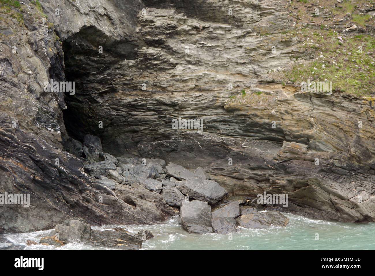 Merlin's Cave sotto il castello sull'isola di Tintagel da Tintagel Haven sul sentiero costiero sud-occidentale in Cornovaglia, Inghilterra, Regno Unito. Foto Stock