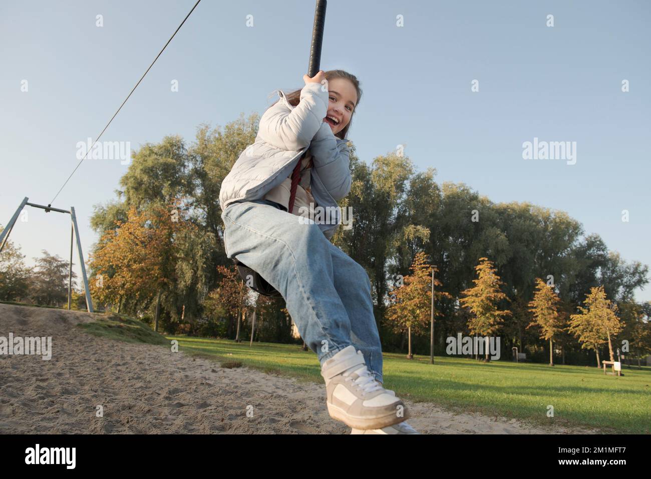 Giovane ragazza in sella a un bungee appeso sul parco giochi. Divertimento autunnale all'aperto. Foto Stock