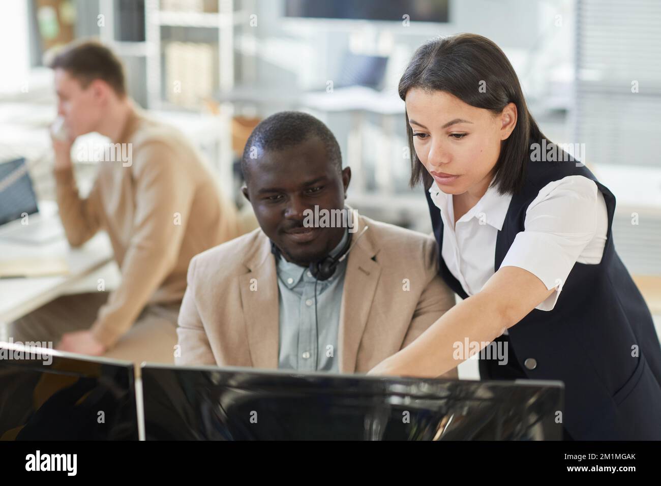Ritratto di una giovane manager che istruisce un dipendente mentre lavora in ufficio e indica lo schermo del computer Foto Stock