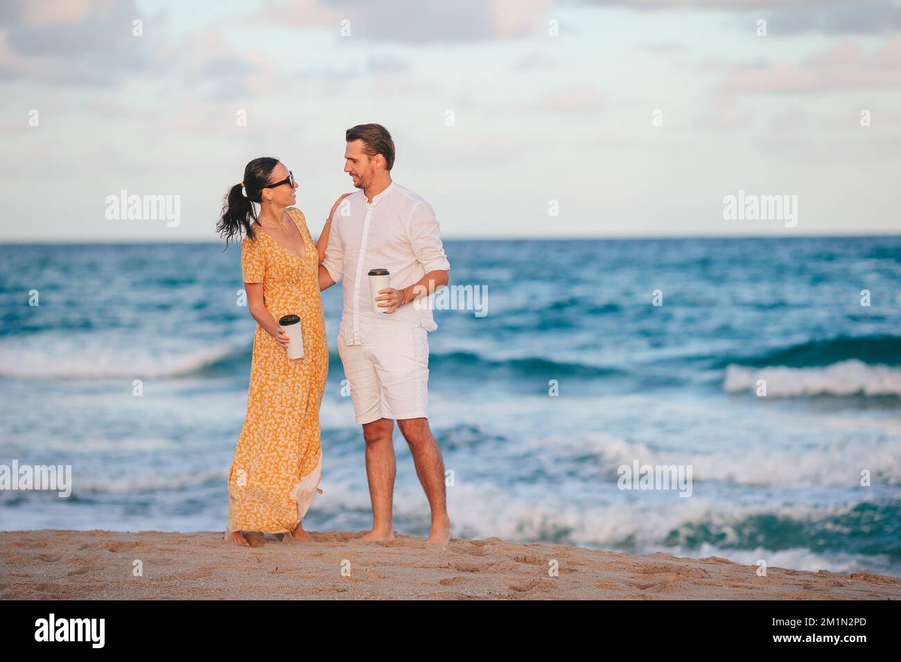 Una giovane coppia in spiaggia si sveglierà e gusterete un caffè Foto Stock