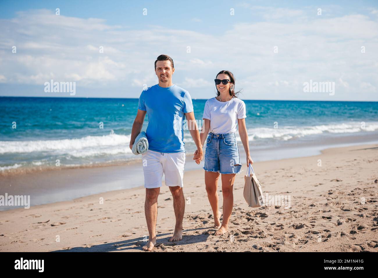 Giovane coppia che tiene le mani a piedi sulla vacanza spiaggia Foto Stock