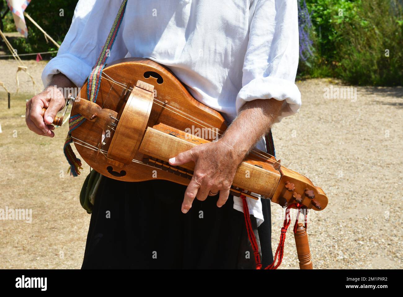 Uomo con uno strumento musicale a ruota in occasione di una rievocazione medievale a Flatford, Suffolk, Inghilterra, Regno Unito Foto Stock