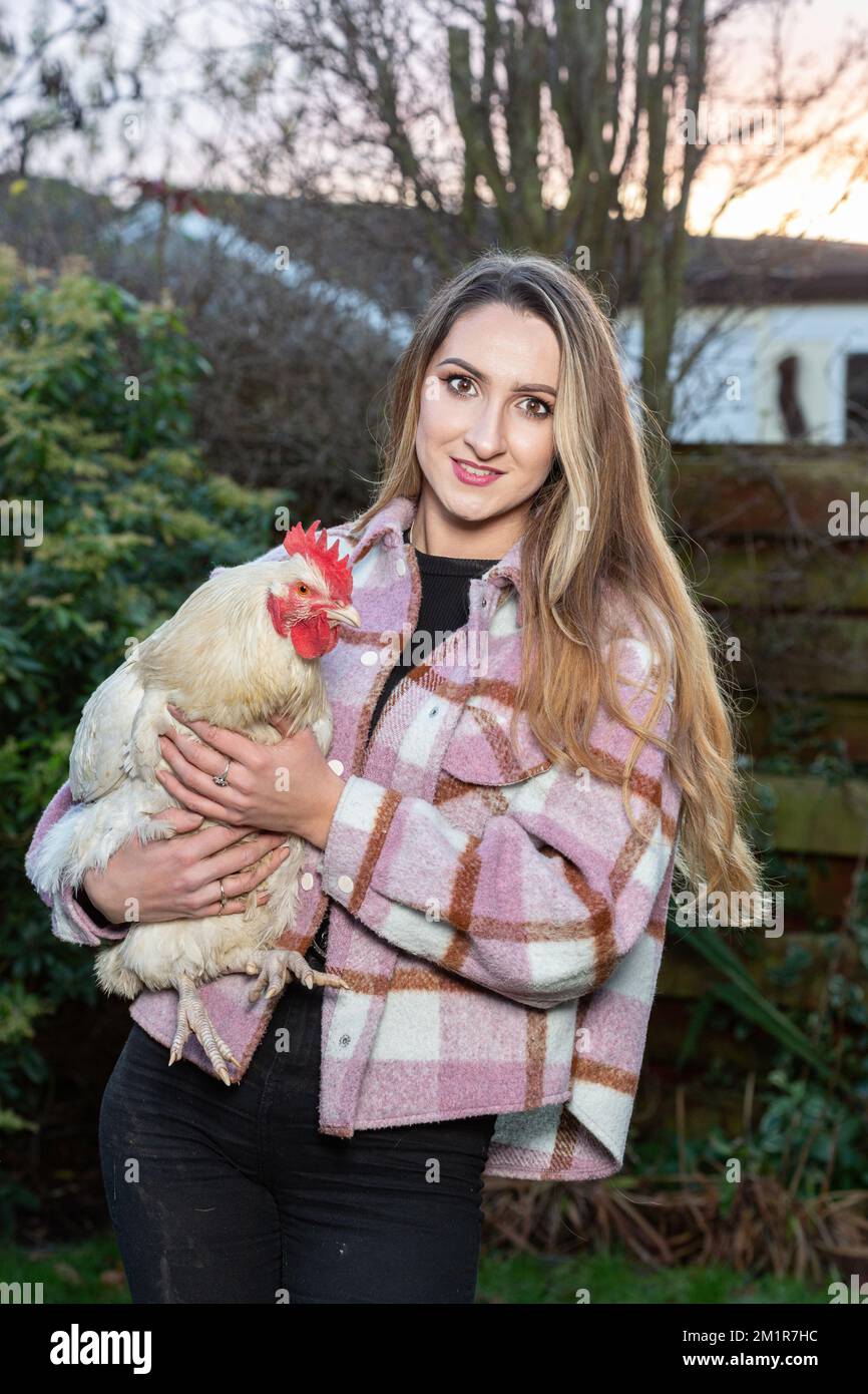 Una giovane donna che tiene un gallo sotto il braccio Foto Stock