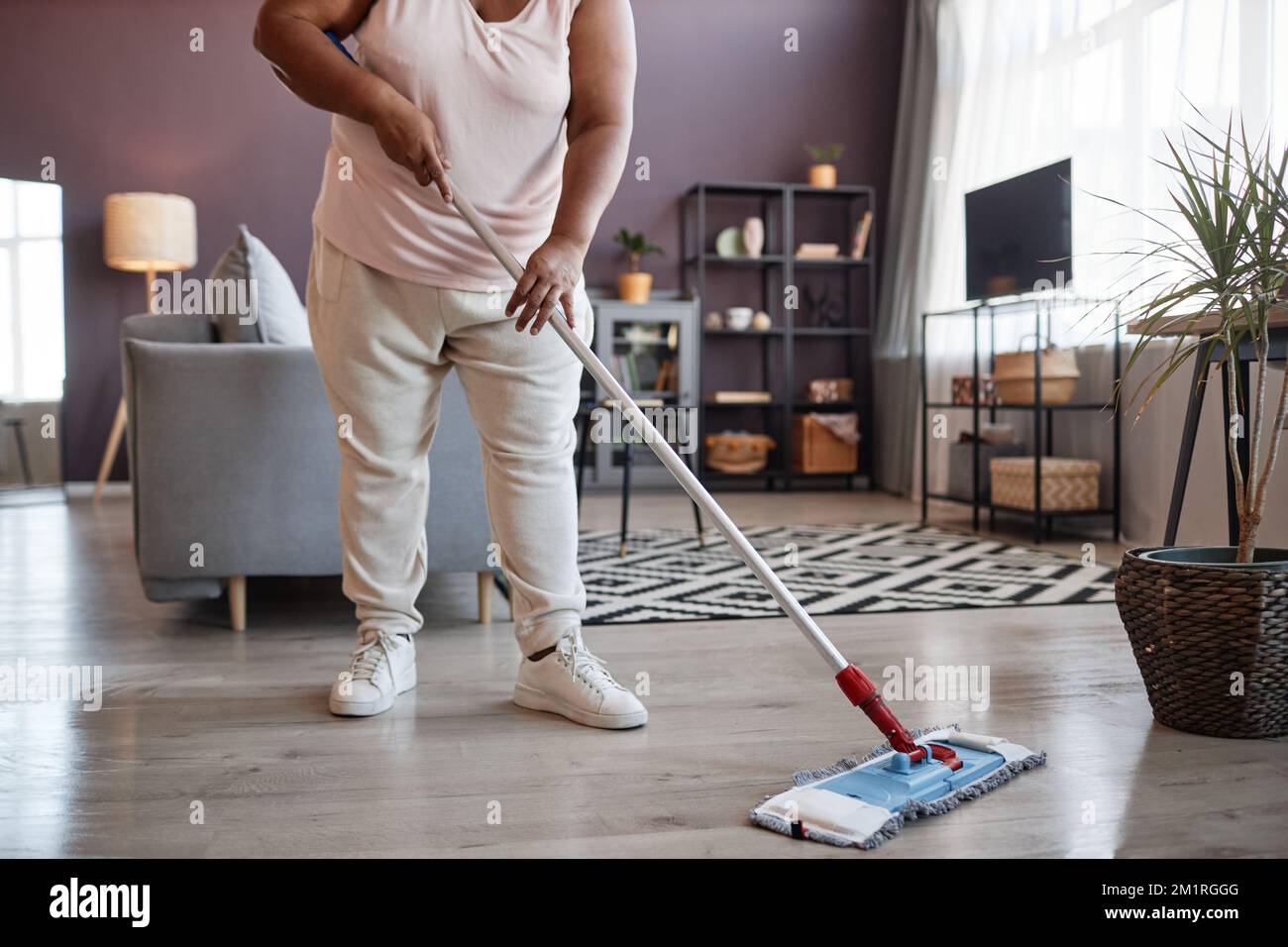 La donna aspira e pulisce il pavimento del tappeto durante le pulizie per  l'igiene sanitaria