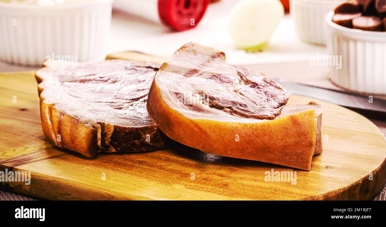 grande pezzo di pancetta cruda e cotta, maiale brasiliano con ingredienti sullo sfondo Foto Stock
