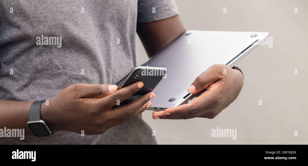 Uomo africano mano leggere il messaggio di testo sul telefono cellulare mentre in ambiente urbano. Foto Stock