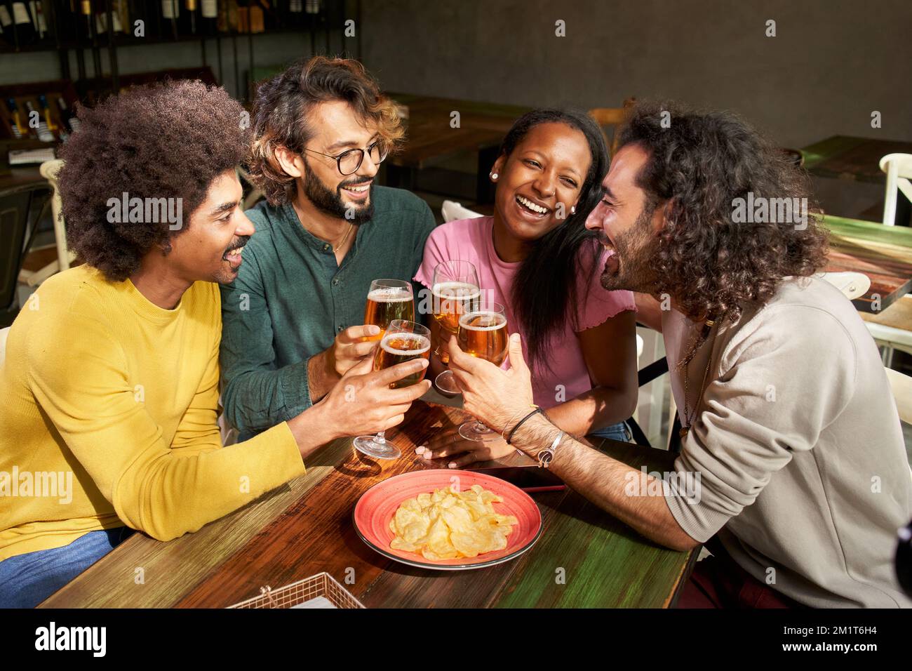 Un gruppo di colleghi brinda con la birra nel bar del ristorante dopo il lavoro all'happy hour del pub Foto Stock