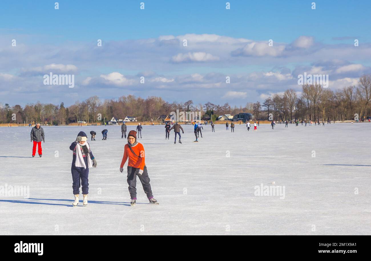 Due giovani donne pattinano sul ghiaccio del lago Paterswoldse Meer a Groningen, Paesi Bassi Foto Stock