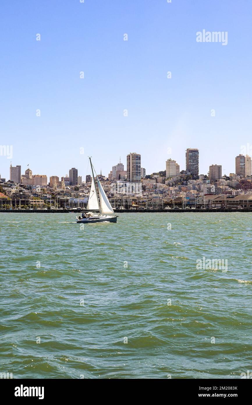 Una vista della città di San Francisco con una barca a vela di fronte alla città su un con un cielo blu chiaro sopra. Foto Stock