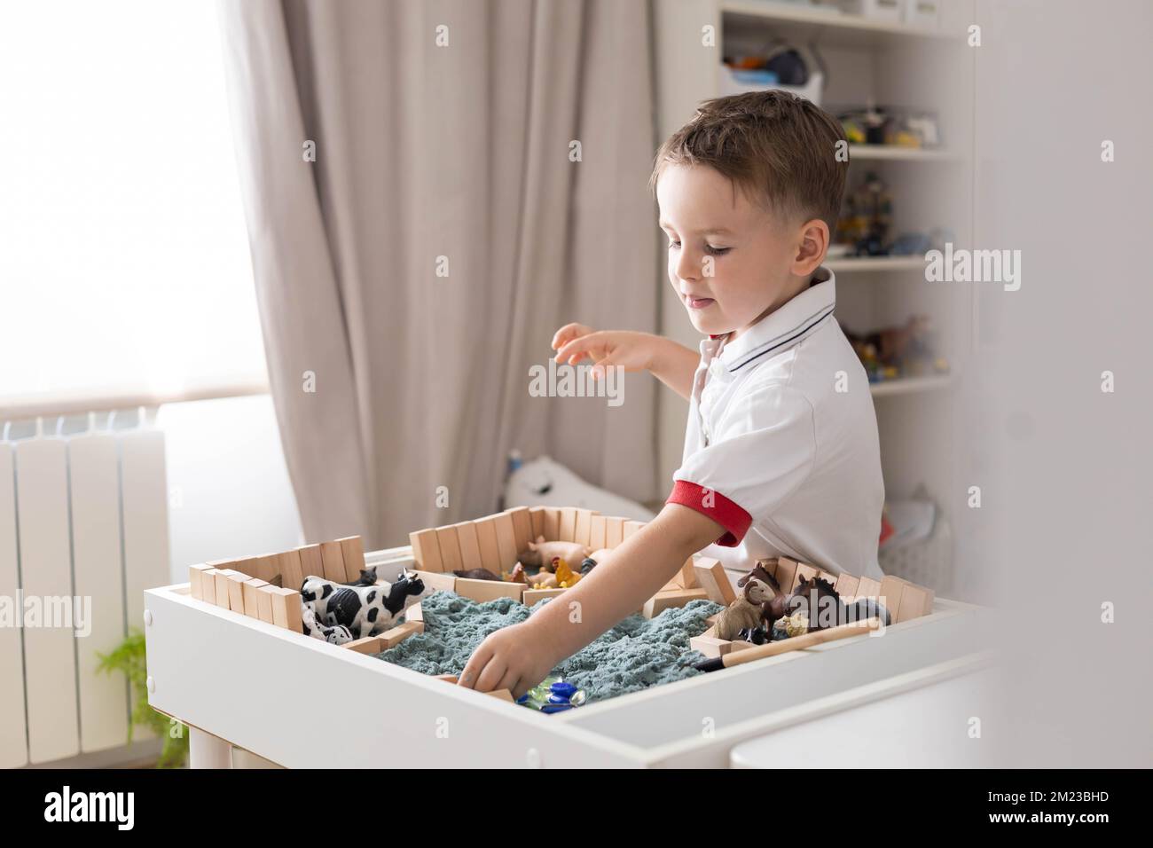 Carino bambino ragazzo giocando sensoriale box cinetica tavolo di sabbia  con animali da fattoria Foto stock - Alamy
