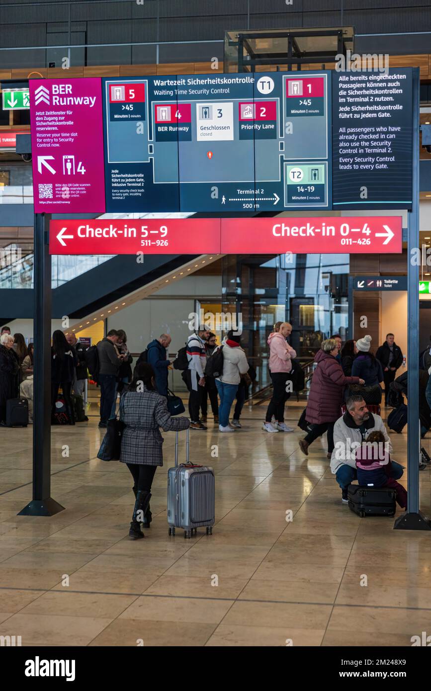 BERLINO, GERMANIA - 12 DICEMBRE 2022: Firma che illustra il controllo di sicurezza e indica i tempi di attesa. I passeggeri dell'aeroporto BER sono ancora di fronte Foto Stock