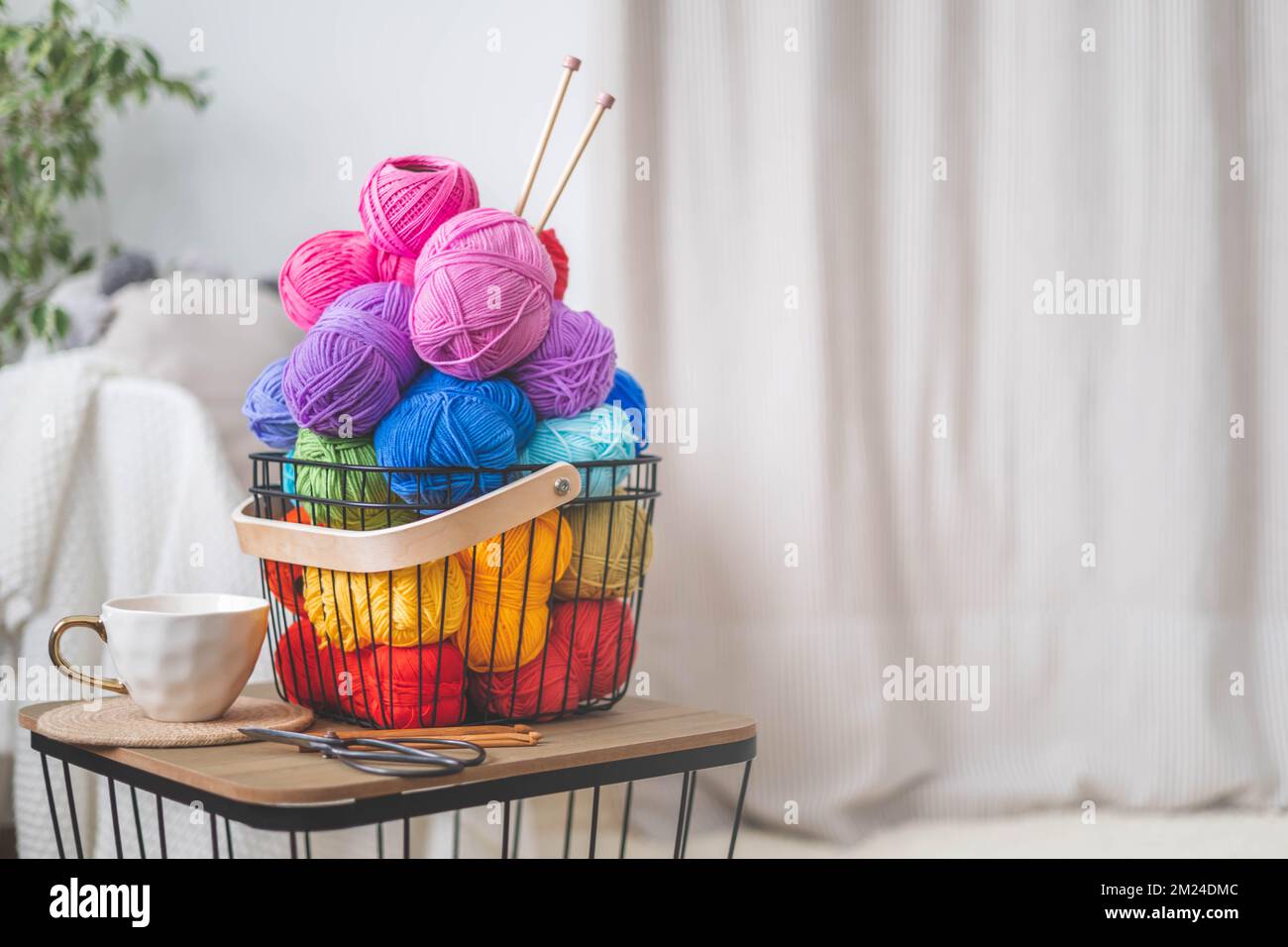 Tanti fili luminosi e colorati per lavorare a maglia e uncinetto in un  elegante cestino in stile scandi Foto stock - Alamy