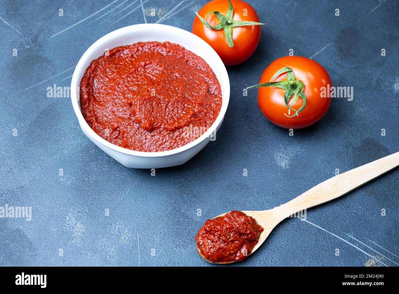 Concentrato di pomodoro, concentrato di pomodoro su cucchiaio di legno, vista dall'alto. Foto Stock