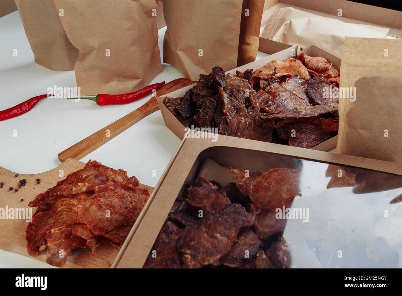 Alcune scatole di cartone artigianali con dolci disidratati per cani, quella più alta è aperta, piena di carne secca sapori croccanti di manzo e pollo. Animale domestico fatto in casa Foto Stock